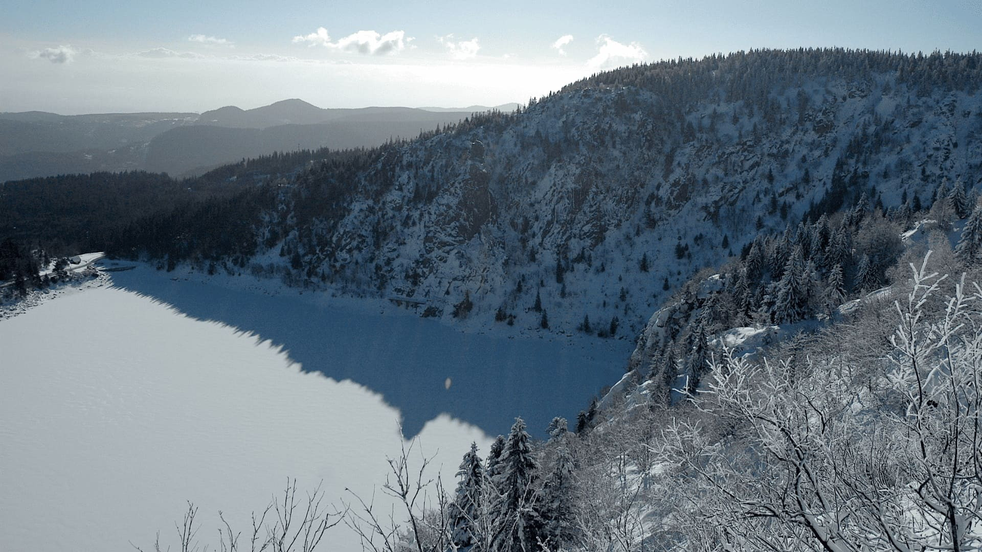 Lac gelé dans un cirque forestier enneigé