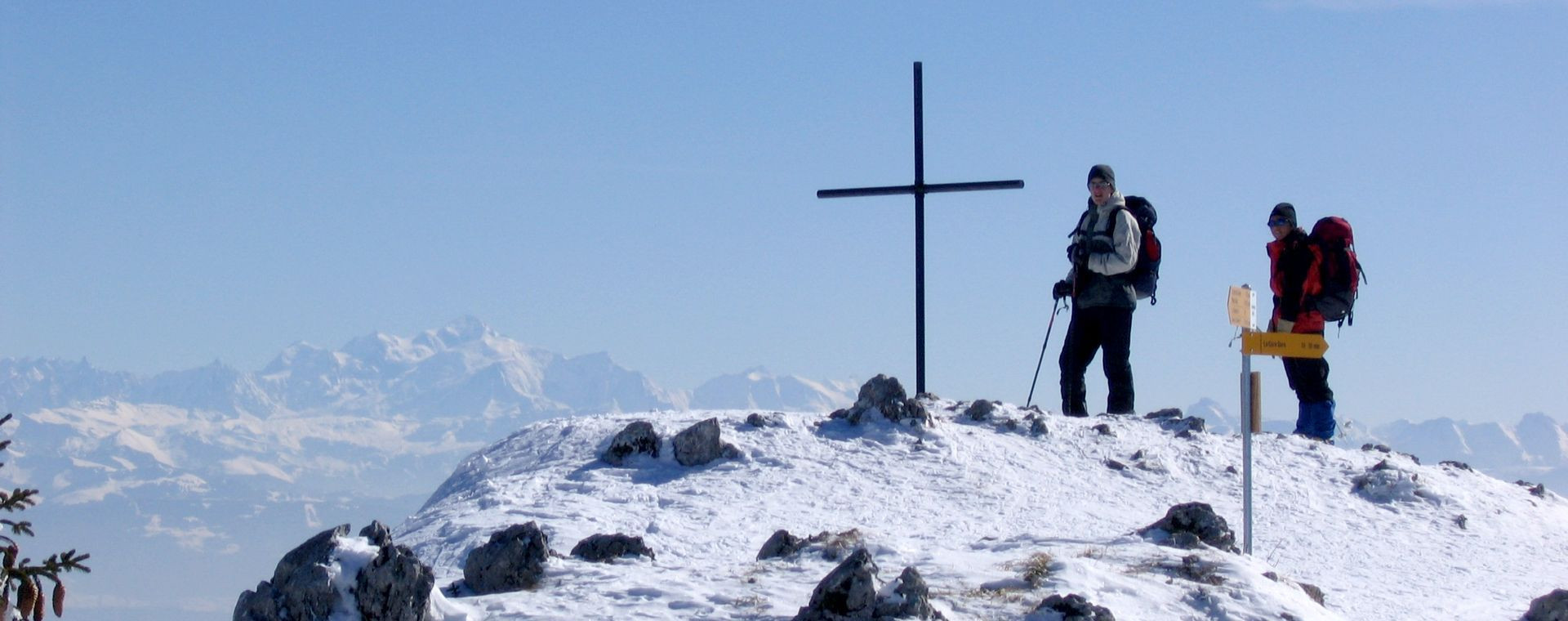 Randonneurs en raquettes près d'une croix sommitale - Jura franco-suisse